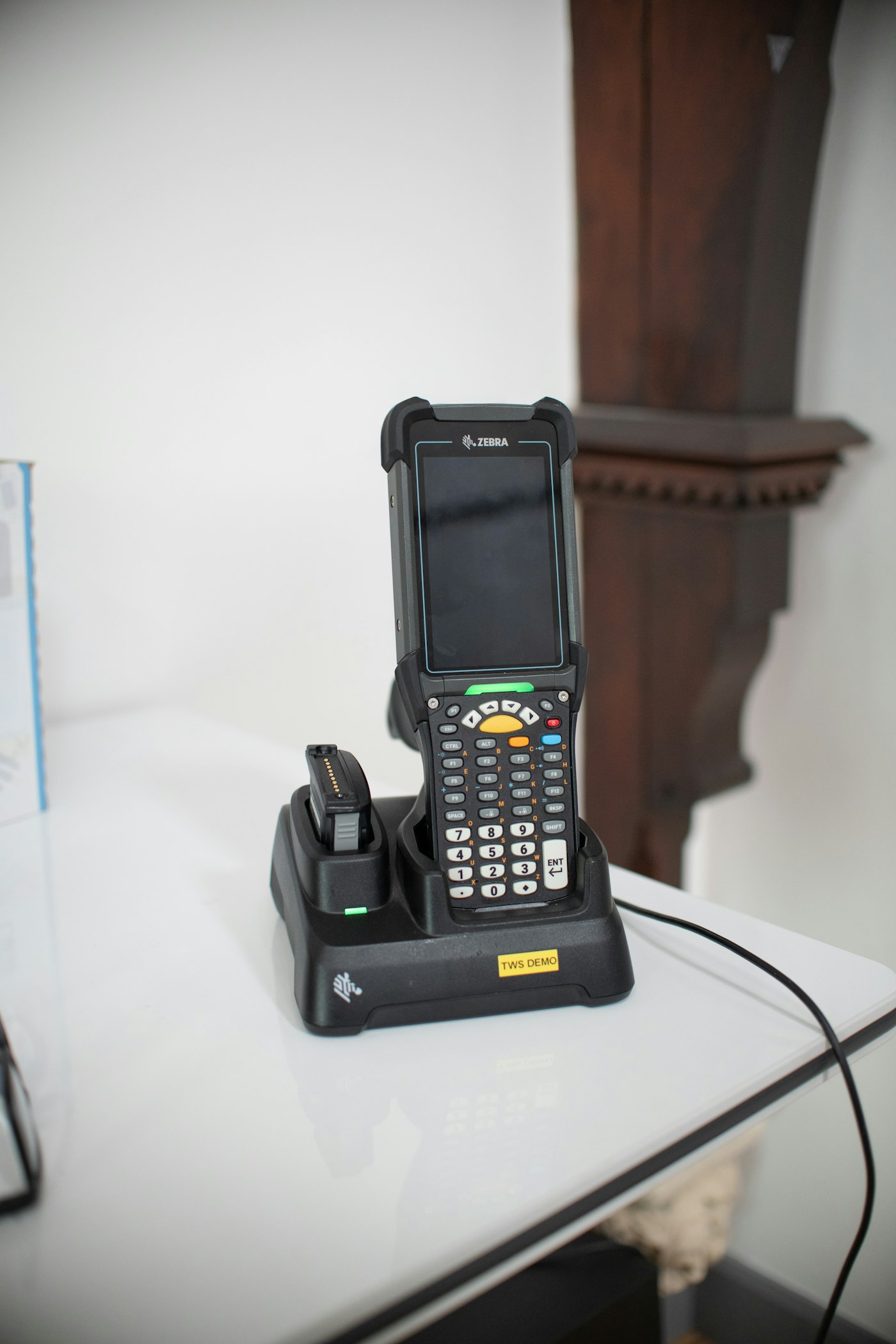 Handheld barcode scanner resting in its charging dock, ready for a receiving shift.